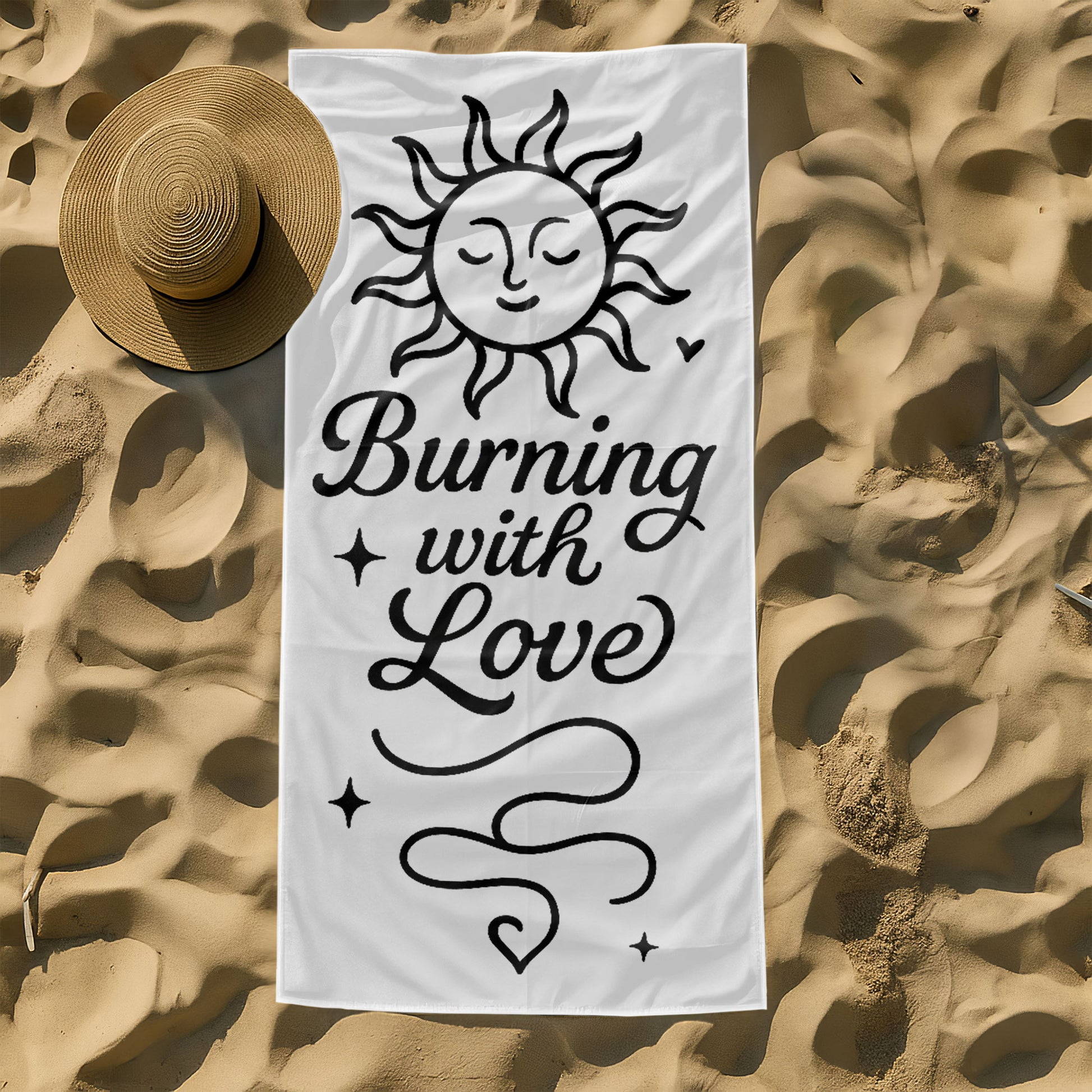 Two people holding up custom white beach towels with black sun and moon designs and romantic phrases, "Burning with Love" and "Falling in Your Gravity," on a sunny beach.