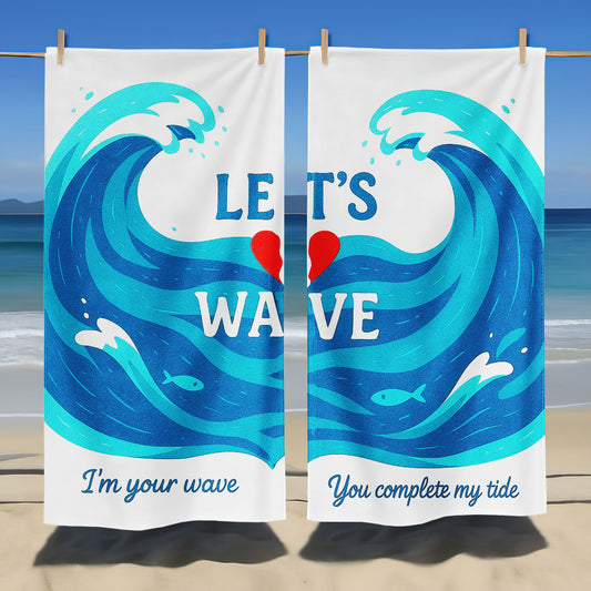 A couple holding up custom white beach towels with large blue wave designs and romantic phrases, "I'm your wave" and "You complete my tide," on a sunny beach.